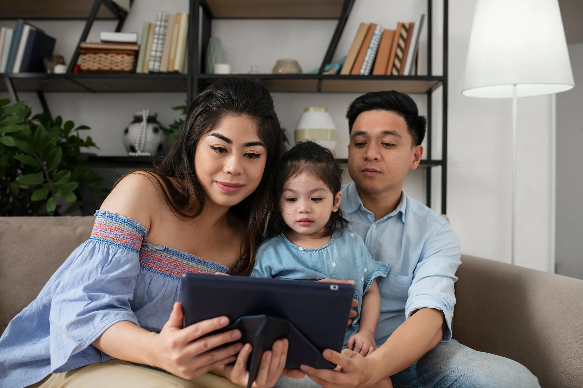Parents looking at a tablet with their daughter